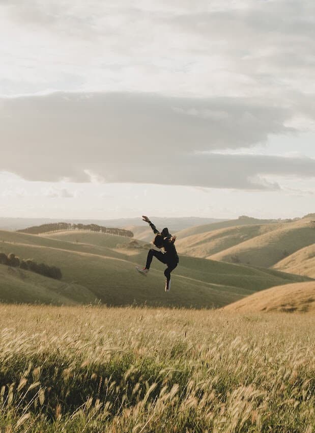person jumping on hillside
